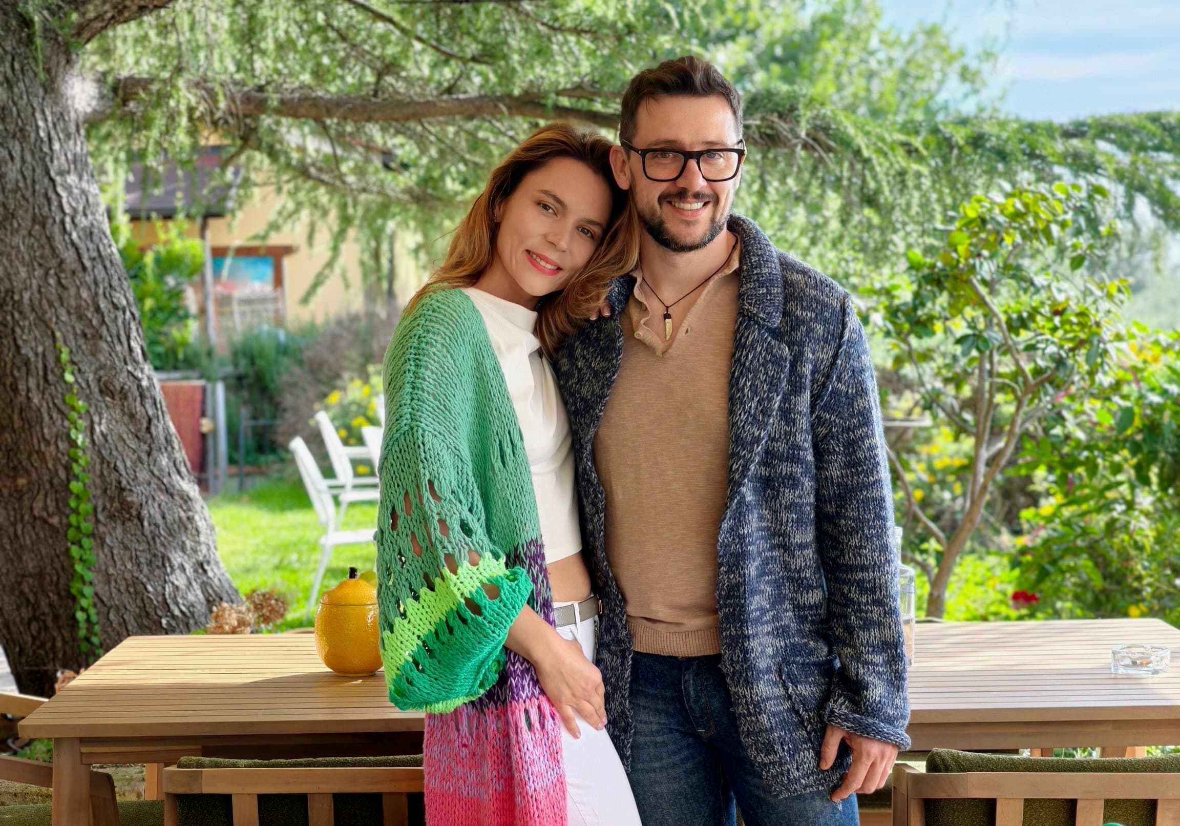 Lorenzo and Sofia, founders of Aura Toscana, standing in the estate gardens surrounded by wild rosemary and Tuscan countryside